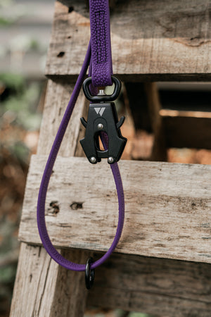 Close-up of a purple Pebble Grip BioThane® leash showcasing a durable clip on a wooden surface.