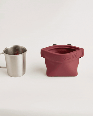 Voilà Standard Ultimate Treat Pouch | 16oz. next to a stainless steel cup, showcasing its versatile design.