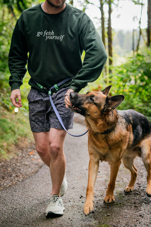 Man walking dog with Atlas BioThane Hands-Free Leash in a scenic outdoor setting.