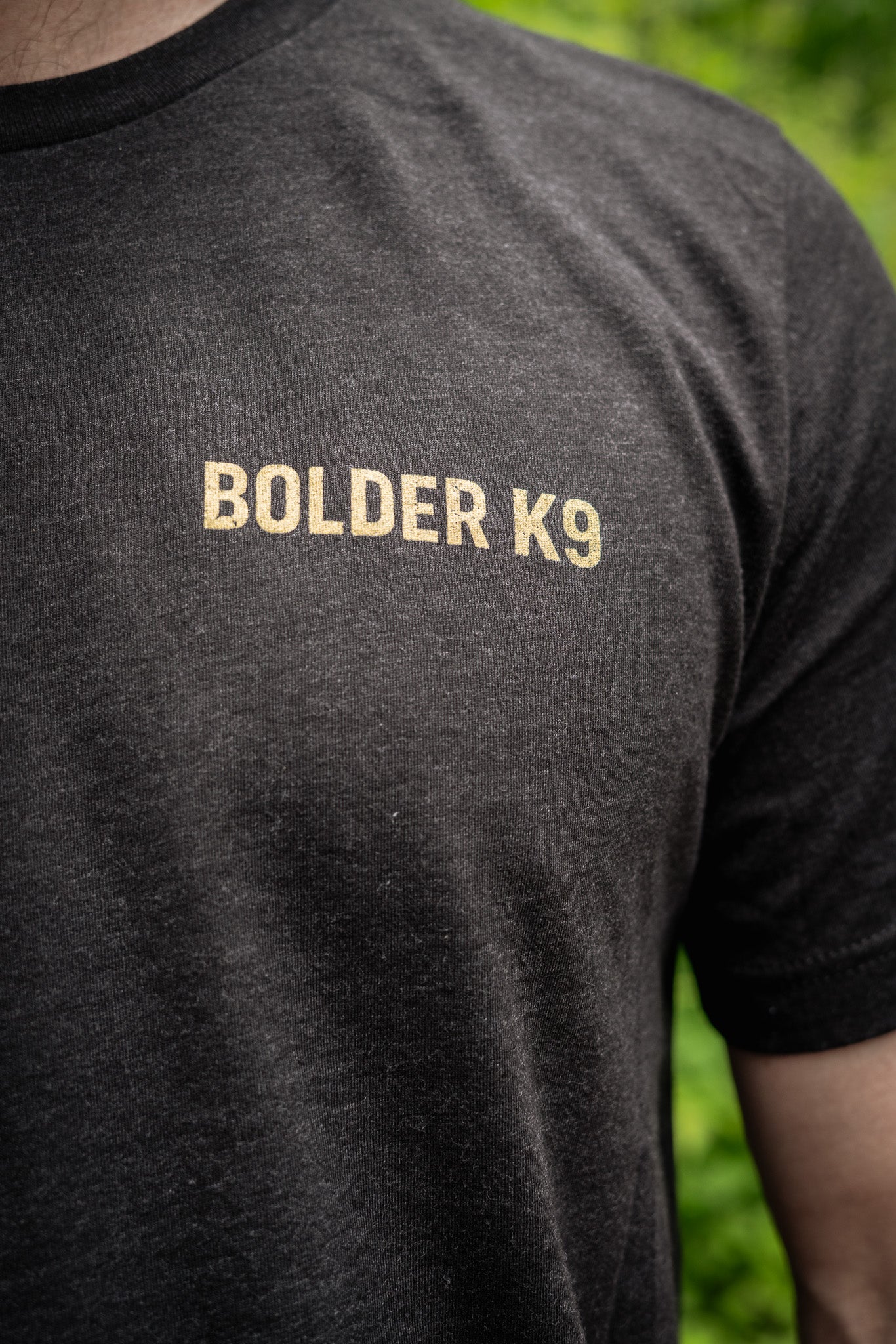Close-up of Bolder K9 logo on heather black t-shirt, showcasing eco-friendly screen-printing.