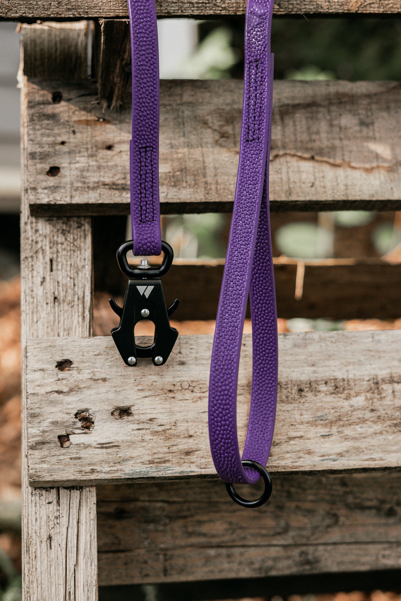 Pebble Grip BioThane® leash in purple with a sturdy metal clasp on a rustic wooden background.